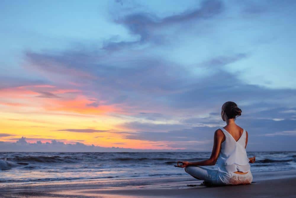 a woman meditating on the beach