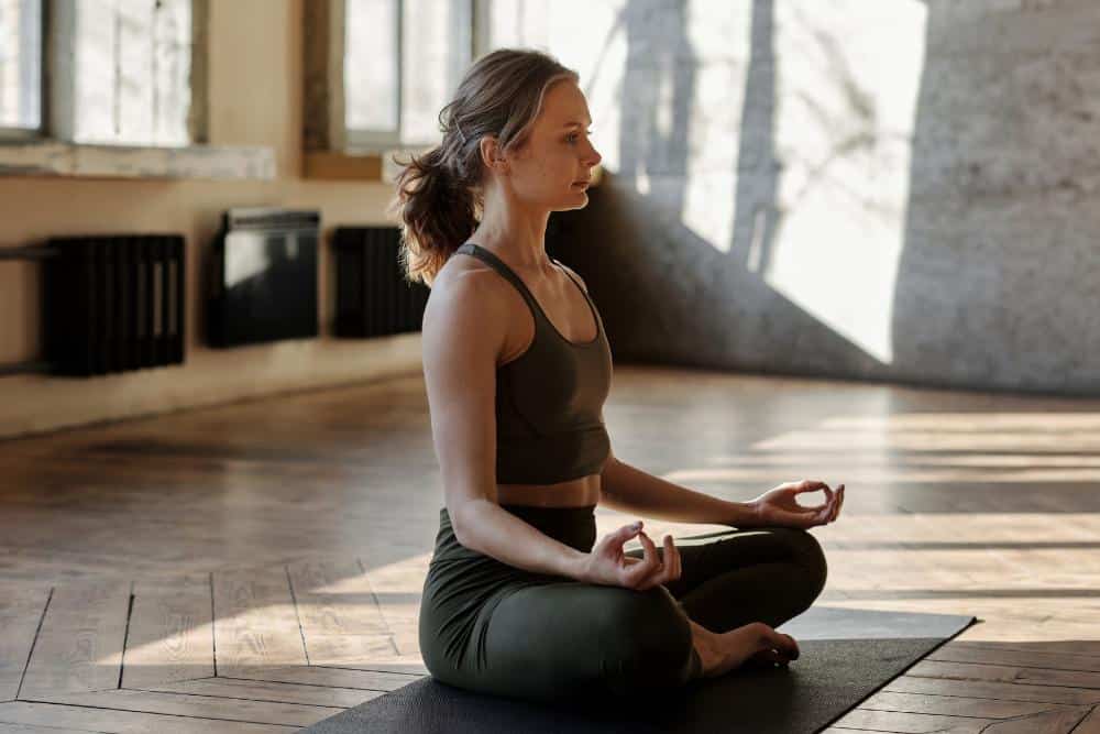 a woman sitting on a yoga mat meditating