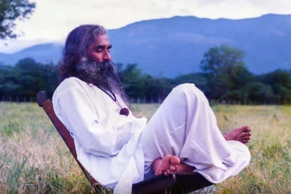 Younger Sadhguru meditating and pondering while sitting on a chair